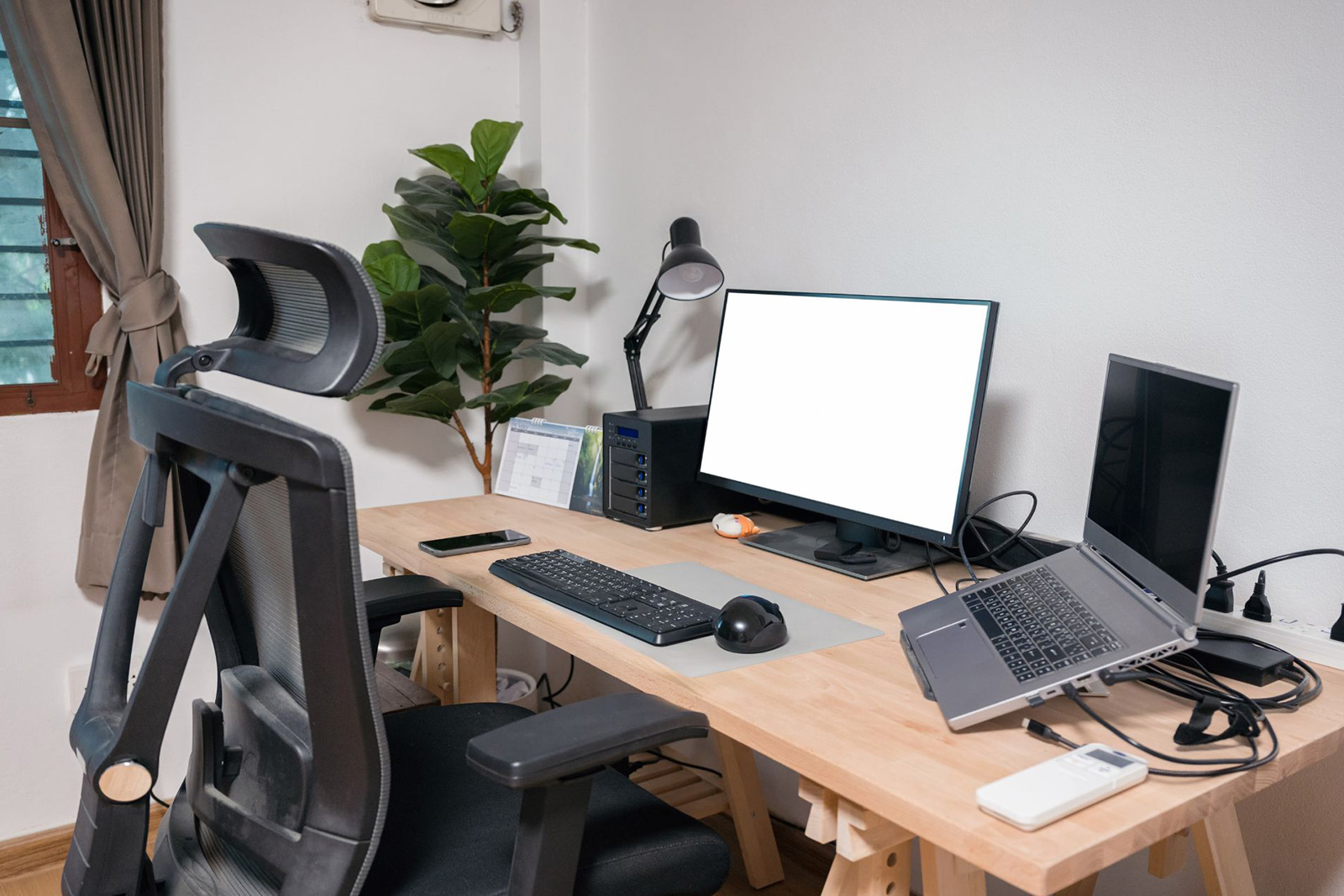 A clean, ergonomic desk setup with a laptop and external monitor.